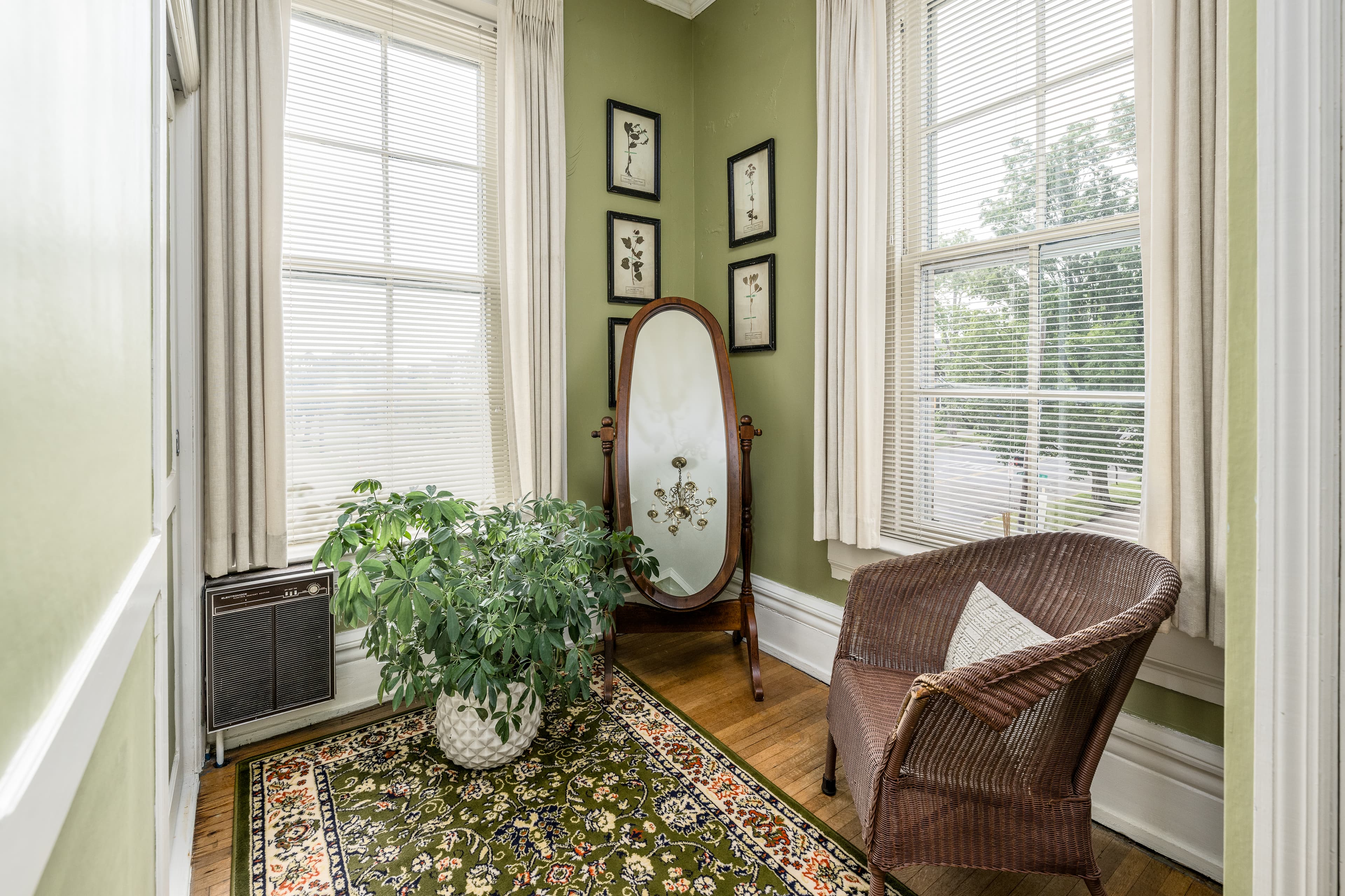 Sitting area with bright windows, brown chair, mirror and plant