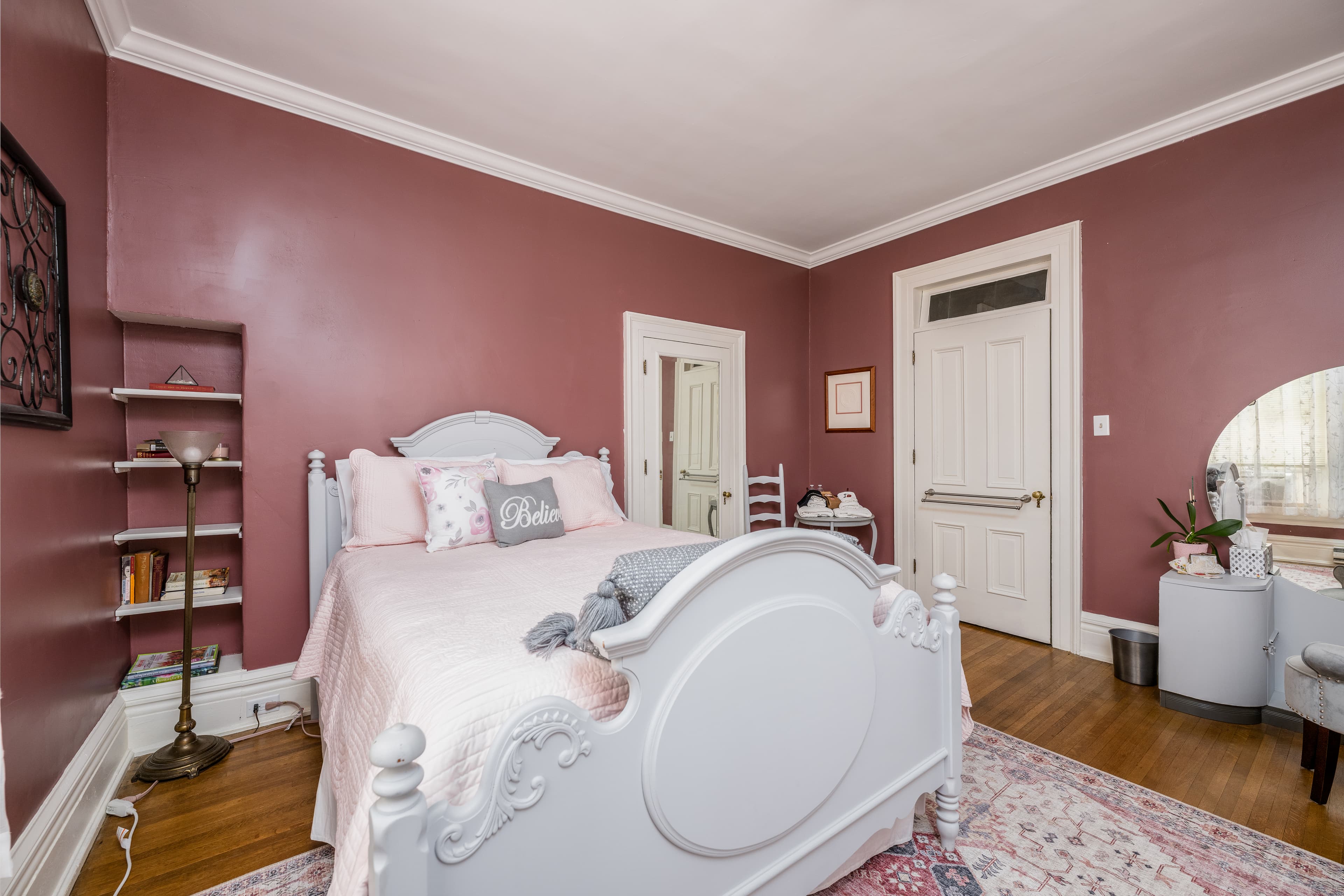 Queen bedroom with dark pink walls and a white bed frame