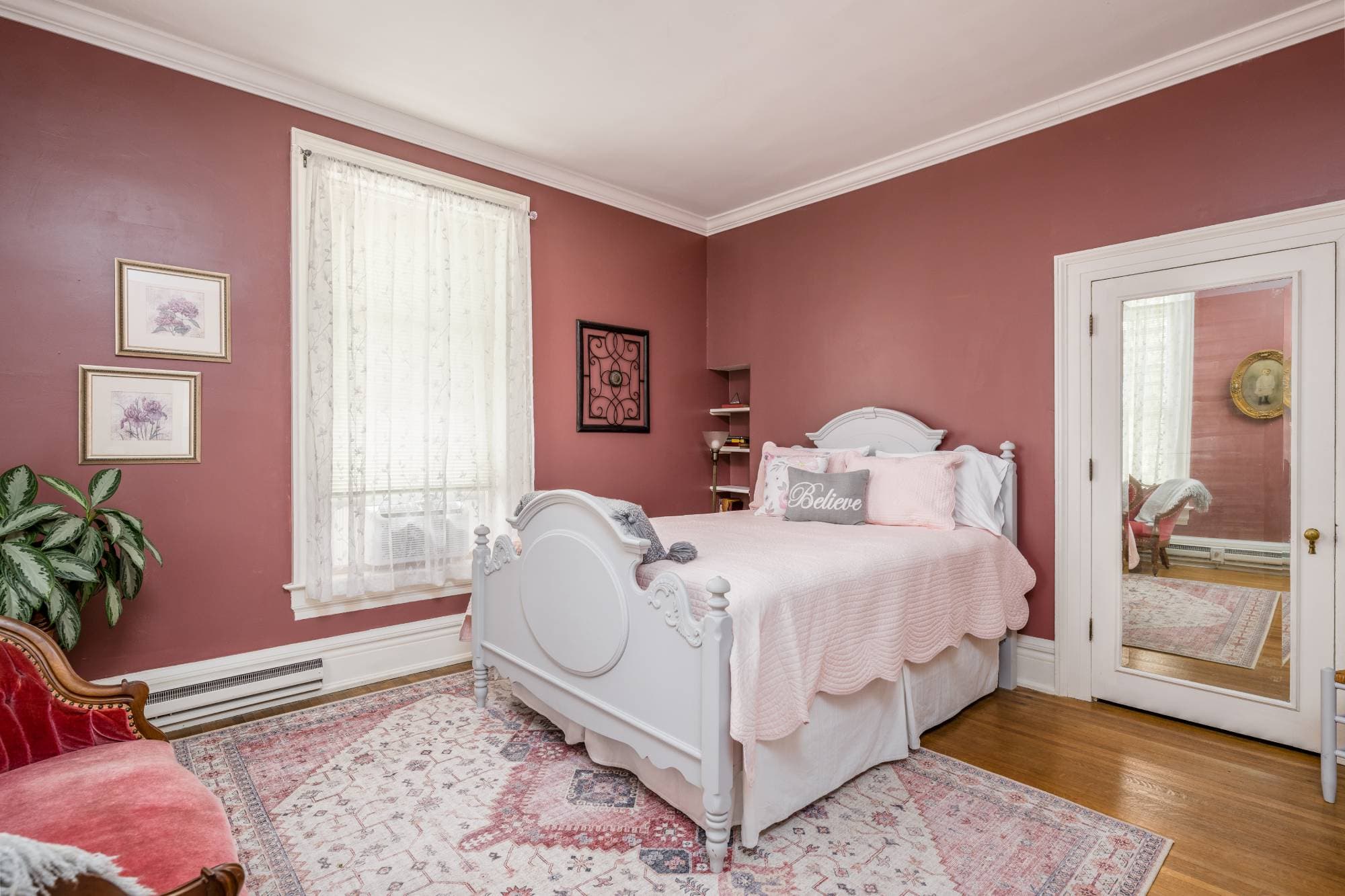 Vintage furnishingsQueen bedroom with dark pink walls and a white bed frame